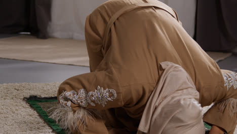 Mujer-Musulmana-Usando-Hijab-En-Casa-Orando-Arrodillada-Sobre-Una-Alfombra-De-Oración-1